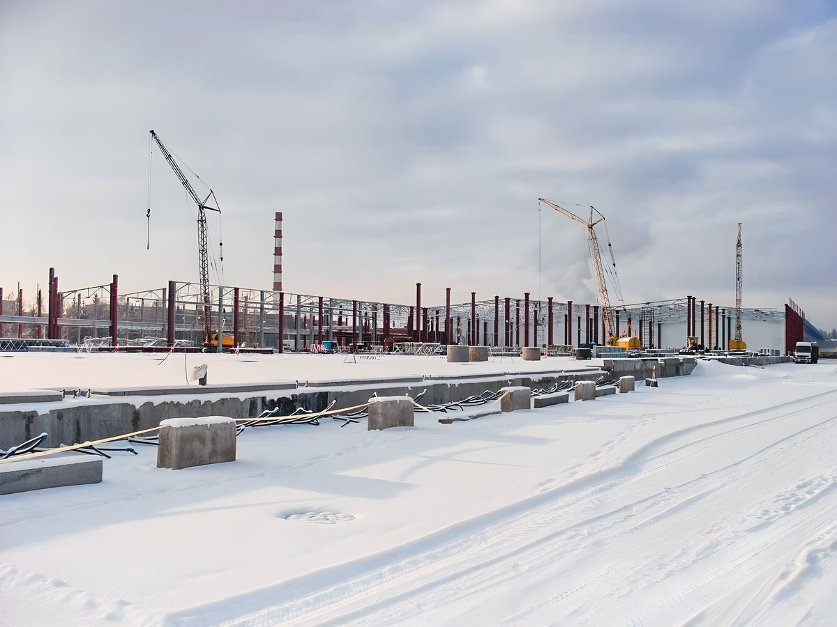 A construction site in winter with cranes and partially built structure